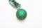 Christmas accessory concept. Ball with glamorous ornaments connected with shimmering green tinsel. Tinsel with christmas