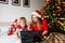 Christmas activity indoor: new year`s online shopping. Mother and son in santa hats look at a laptop and choose gifts, sitting on