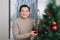 Christmas. Asian man standing new christmas tree at home celebrating New Year.