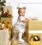 Christmas baby child toddler near gold christmas tree presents a