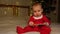 Christmas Baby in red Santa costume playing on white soft bed. Smiling 7 month newborn baby in Santa Claus bodysuit