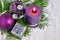 Christmas background with candle and decorations.Purple and silver Christmas balls over fir branches in the snow