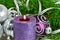 Christmas background with candle and decorations. Purple and silver Christmas balls over fir tree branches in the snow