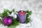 Christmas background with candle and decorations.Purple and silver Christmas balls over fir tree branches in the snow