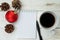 Christmas background. Fir cones, red ball, notebook and pen on white wooden background. Note form