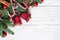 Christmas background with fir tree, christmas bells, candy, red berries and pine cones on white wooden table