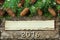 Christmas background of fir tree and conifer cone on old vintage wooden board, fantastic snow effect, wooden numbers of New year a