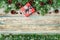 Christmas background with gift box, fir branch and conifer cone on wooden rustic board, festive snow effect, Christmas frame