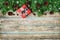 Christmas background with gift box, fir branch and conifer cone on wooden rustic board, festive snow effect, Christmas frame