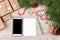 Christmas background with gift boxes, mobile phone with back screen and blank notebook, copy space. Template for new year goal or