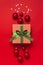 Christmas background. Gift with green ribbon, red Christmas balls, confetti shape of stars on red background top view. New Year