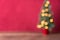 Christmas background, intentional blur of lit Christmas tree on wood table against red background