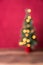 Christmas background, intentional blur of lit Christmas tree on wood table against red background