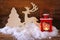 Christmas background with red lantern, wooden decorative reindeer and tree on the snow over wooden background.