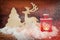 Christmas background with red lantern, wooden decorative reindeer and tree on the snow over wooden background.