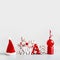 Christmas background with Santa hut, word  Xmas, candles and red holiday ball stand on light gray background. Modern still life.