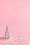 Christmas background with small silver Christmas tree and colorful glitters on pink