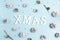 Christmas background with snow painted pine cones and title on blue.