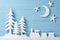 Christmas background with white Christmas trees, toy train, snow, moon and stars, blue wooden background