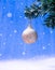 Christmas ball with glitter covered in snow hanging on the fir branch