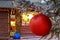 Christmas ball hanging on a snowy tree with Christmas market chalets in the backgr