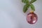 Christmas ball with pink sequins inside, Christmas tree branch on a white background. Copy space.