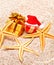 Christmas ball, starfishes and a gift box on sand