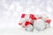 Christmas baubles and red gift boxes over snow bokeh background