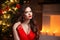 Christmas. Beautiful smiling woman. Fashion ruby earrings jewelry. Makeup. Healthy long hair style. Elegant lady in red dress