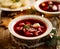 Christmas beetroot soup, borscht with small dumplings with mushroom filling in a ceramic bowl on a wooden table, top view.