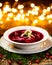 Christmas beetroot soup, red borscht with small dumplings with mushroom filling in a ceramic white plate on a wooden table.
