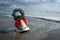 Christmas Bell with Wreath and Red Bow in the Sand at the Ocean with Foamy Waves