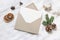 Christmas blank greeting card mock-up scene. Festive winter wedding composition. Craft envelope, pine cone, dry orange