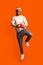 Christmas Bonus. Positive Black Guy With Gift Box Jumping Over Orange Background