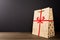 Christmas Brown Paper Bag with Red Ribbon and glittering golden trees on wooden table isolated on black background, glittering