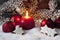 Christmas bulbs cinnnamon stars pine twig candle on pile of snow against wooden wall