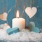 Christmas candle in white with blue hearts, wood and snow for de