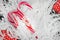 Christmas candy canes and red gift boxes illuminated by garland and placed on white paper sawdust