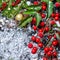 Christmas card of berry with snow, evergreen branches, red leaves and gold ball, closeup