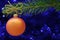 Christmas card concept. Orange Christmas bauble and spruce branch with copy space.