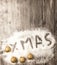 Christmas card with the inscription xmas golden balls in the snow on a wooden background.