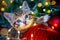 Christmas cat. Portrait striped kitten playing with Christmas lights garland on festive red background. Kitty looking at