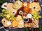 Christmas Cheese board appetizers platter with various types of cheese, crackers, jam, fruits and pistachios on a dark background