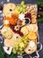 Christmas Cheese board appetizers platter with various types of cheese, crackers, jam, fruits and pistachios. Overhead view, cope