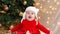 Christmas child pensively, dreamily surprised looks up. A cute little girl in a red dress and white hat expresses emotions.