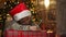 Christmas child writes a letter to Santa Claus. A child in a Christmas hat writes a wish list of gifts on the background