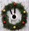 Christmas clock made of fir branches, clock hands of pine nuts, a cup of coffee and Christmas toys on a white wooden