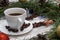 Christmas clock made of fir branches, clock hands of pine nuts, a cup of coffee and Christmas toys on a white wooden