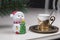 Christmas coffee concept. Golden coffee cup, toy snowman and new year tree branch on table in cafe. Luxurious elegance