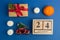 Christmas composition. Calendar with toy car, gift, mandarins, candle on blue trendy background. Festive backdrop for projects.